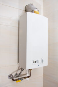 White tankless water heater installed on a white tile wall in a home